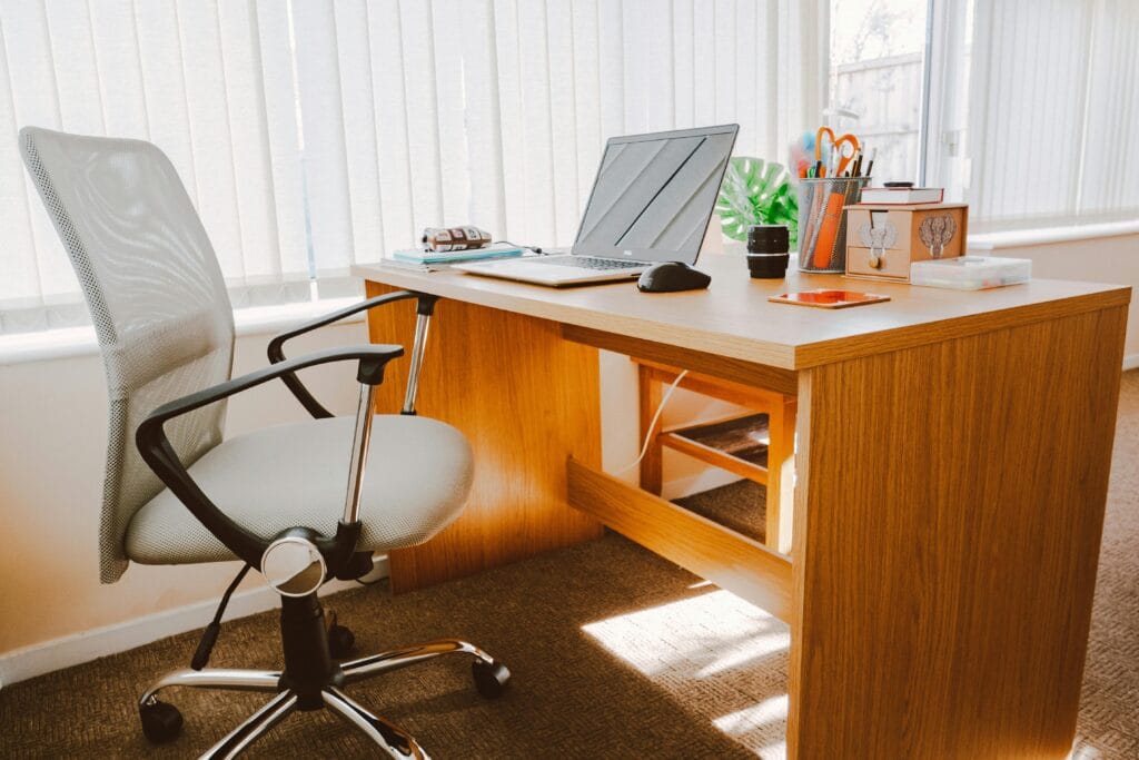 bureaux A modern office workspace featuring a wooden desk, chair, laptop, and bright natural light.
