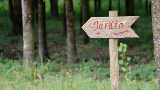 Accueil Rustic wooden sign with 'Jardin' indicating garden path in forested area.