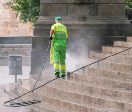 Nettoyage à haute pression A municipal worker power washing stone steps outdoors, ensuring cleanliness and maintenance.